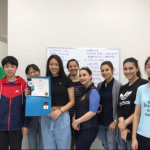 students and a teacher are standing in front of the white board